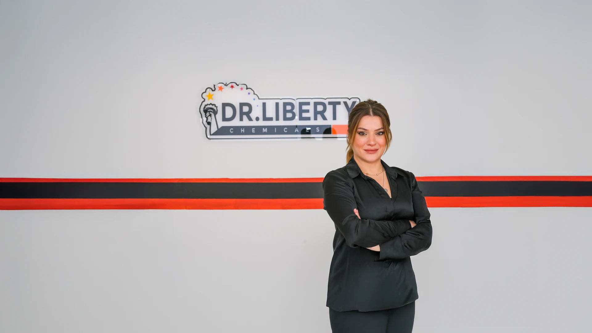 Çiğdem Küçükarık, Dr. Liberty Chemicals logosunun asılı olduğu ofis duvarının önünde
